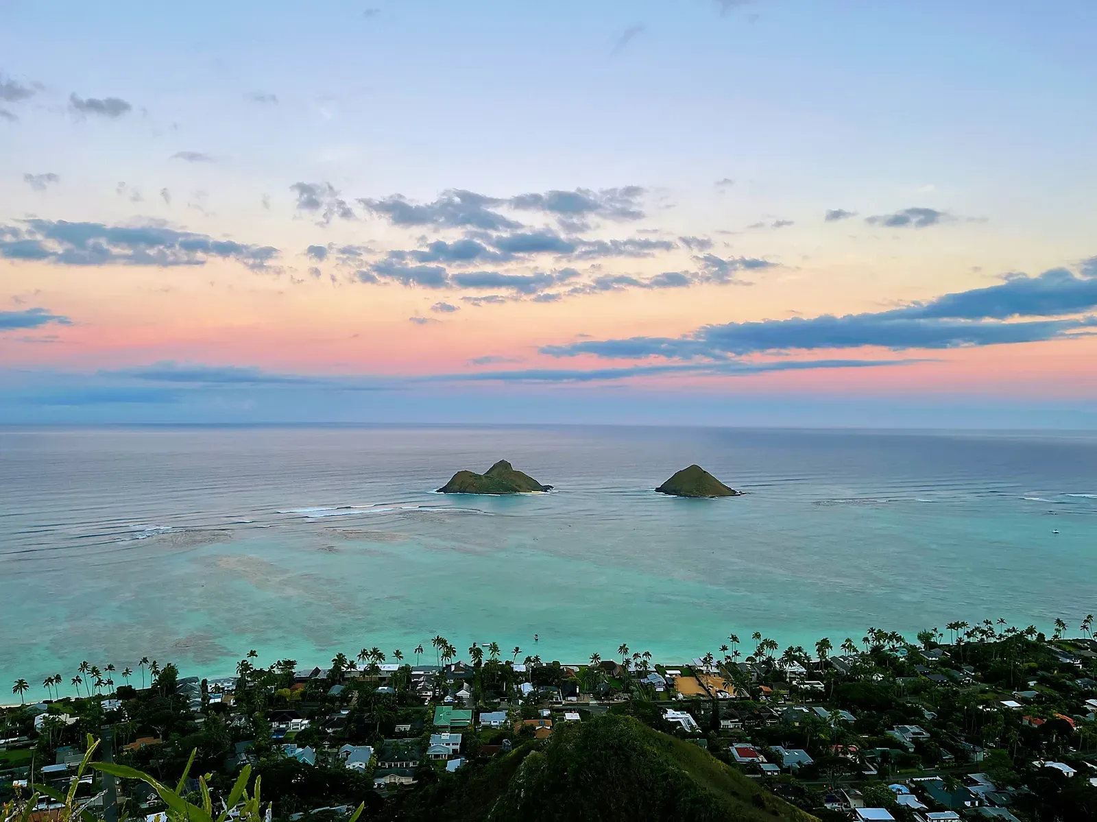 Two islets offshore at dawn above a coastal neighbourhood.